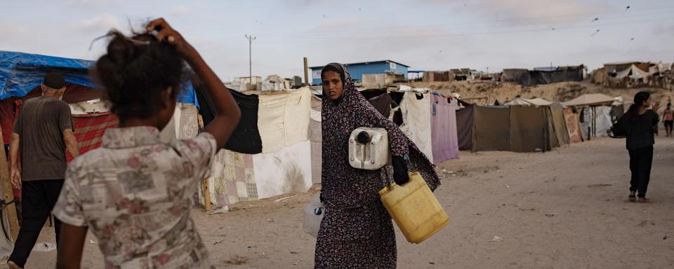 Des personnes déplacées dans un camp de réfugiés du sud de la bande de Gaza, le 27 juin 2024. [Keystone - HAITHAM IMAD]