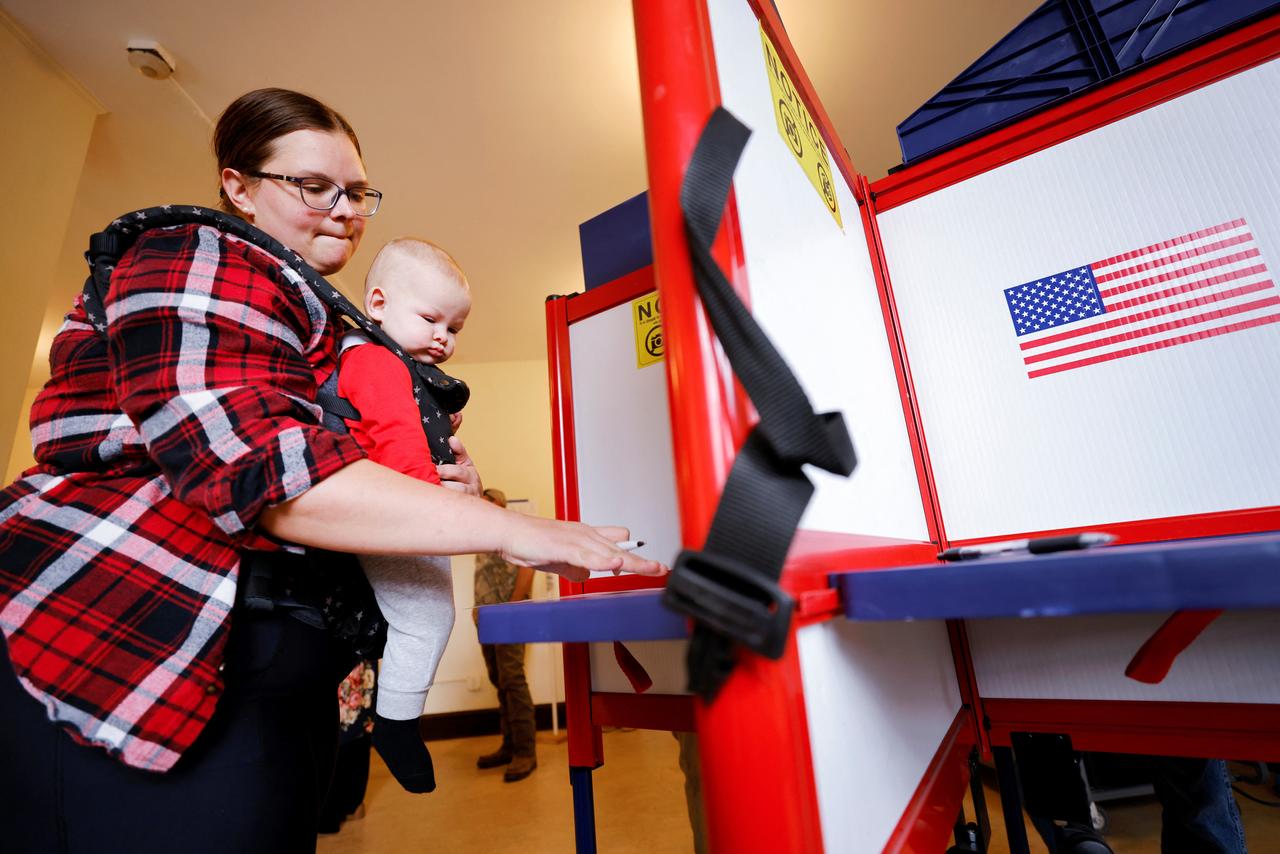 Une femme avec un enfant vote à Leicester, Caroline du Nord, le 5 novembre 2024, à l'occasion de l'élection présidentielle américaine. [REUTERS - Jonathan Drake]