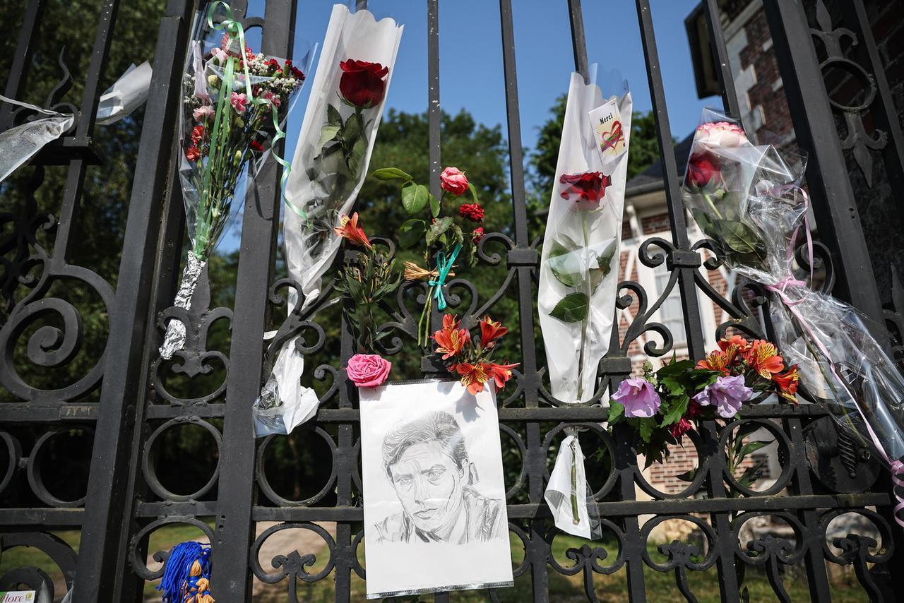 Des fleurs et un portrait devant la porte de la propriété d'Alain Delon à Douchy en France, au lendemain de l'annonce de son décès. [KEYSTONE - CHRISTOPHE PETIT TESSON]