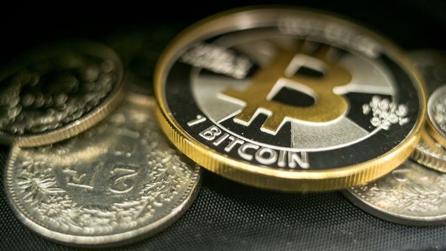 Une pièce symbolique de bitcoin et plusieurs pièces de deux francs. [KEYSTONE - ALEXANDRA WEY]