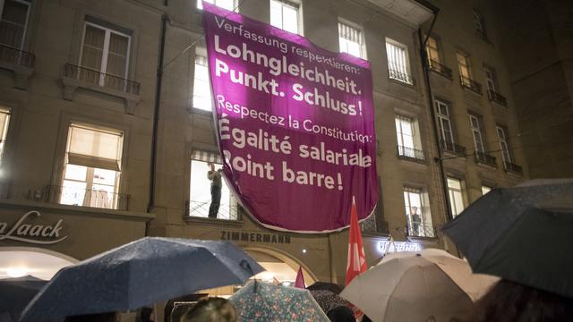 Une affiche avec les inscriptions "Respecter la Constitution : Égalité salariale point. Stop!" et "Respectez la constitution : Égalité salariale. Point barre!" après le 13e Congrès des femmes de l'USS, le vendredi 19 janvier 2018 sur la place du Théâtre à Berne. [Keystone - Anthony Anex]