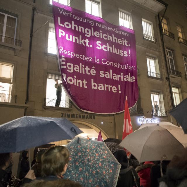 Une affiche avec les inscriptions "Respecter la Constitution : Égalité salariale point. Stop!" et "Respectez la constitution : Égalité salariale. Point barre!" après le 13e Congrès des femmes de l'USS, le vendredi 19 janvier 2018 sur la place du Théâtre à Berne. [Keystone - Anthony Anex]