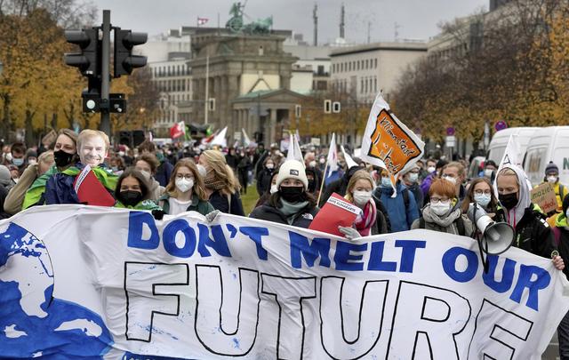 Des personnes manifestaient vendredi en faveur du climat devant la Porte de Brandenburg à Berlin. [AP Photo - Michael Sohn]