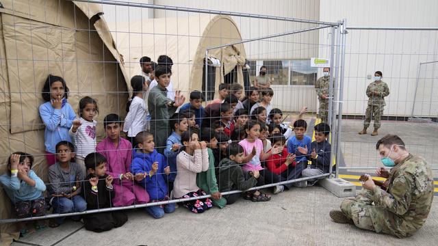 Un soldat américain joue de la guitare pour des enfants récemment évacués d'Afghanistan. Base américaine de Ramstein, Allemagne, le 24 août 2021. [AP Photo - Matthias Schrader]