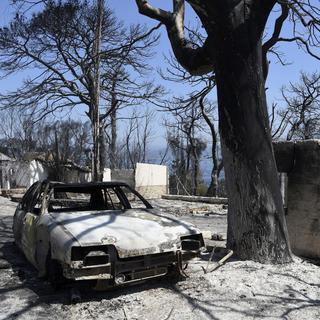 Une voiture et des maisons calcinées après un incendie dans le village de Lampiri en Grèce. [AP Photo - Andreas Alexopoulos]