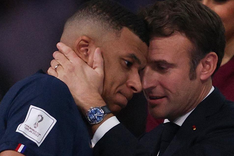 Le président français Emmanuel Macron fait une accolade au joueur français phare de cette finale de Coupe du monde, Kylian Mbappé [AFP - ADRIAN DENNIS]