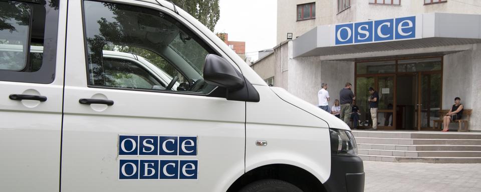 Un bus de l'OSCE photographié devant un bâtiment de l'OSCE en Urkaine. [Keystone - Anthony Anex]