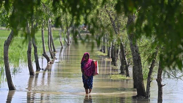 Une femme marche les pieds dans l'eau après le passage du cyclone Sitrang au Bangladesh [AFP - MUNIR UZ ZAMAN]