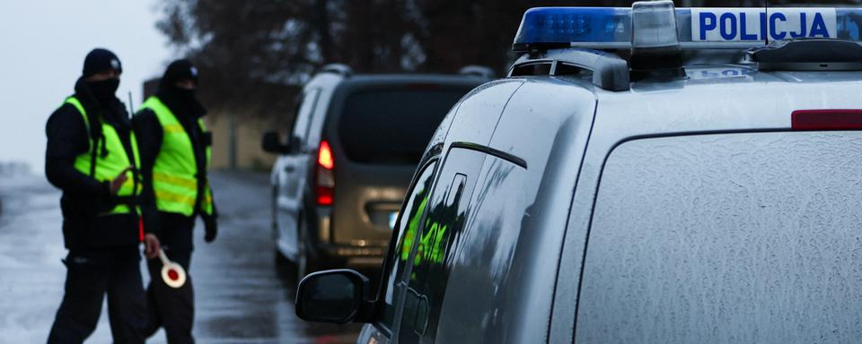 Deux policiers polonais près du lieu de l'impact du tir de missile dans le village de Przewodow. [Reuters - Kacper Pempel]