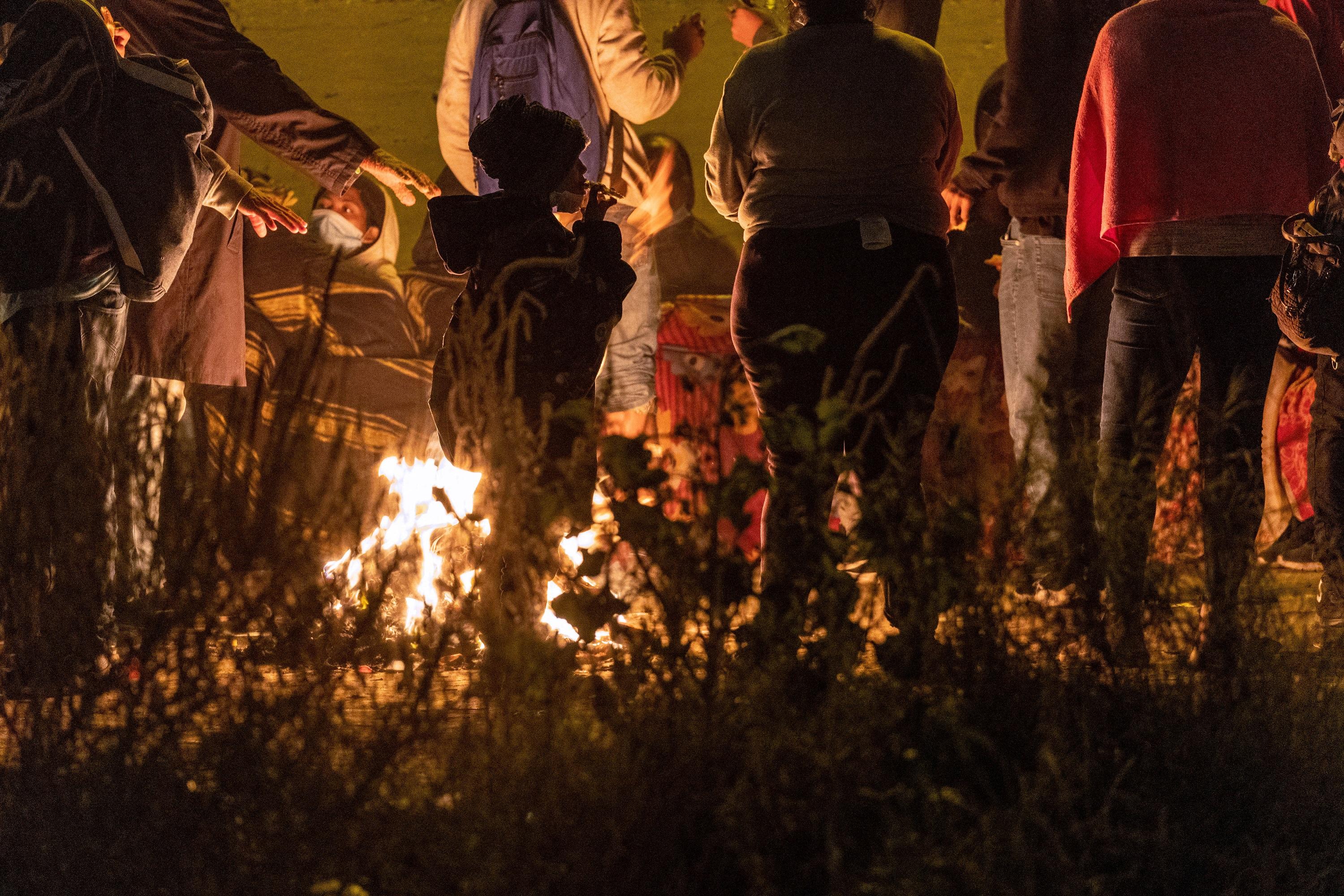 Des migrants se réchauffent autour d'un feu à Ciudad Juarez, à la frontière entre le Mexique et les Etats-Unis, le 19 décembre [GETTY IMAGES VIA AFP - JOHN MOORE]
