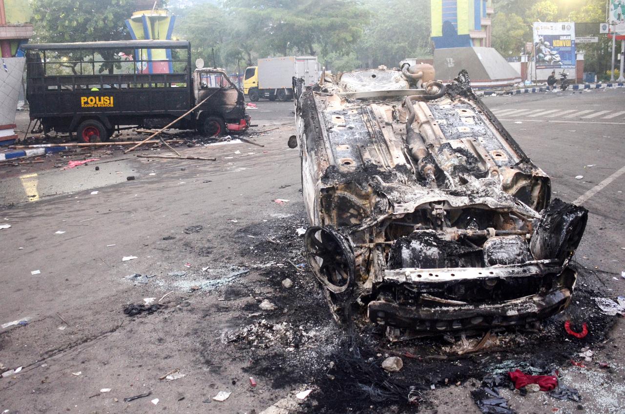 Véhicules de police brûlés en dehors du stade Kanjuruhan à Malang, le 2 octobre 2022. [AFP - PUTRI]