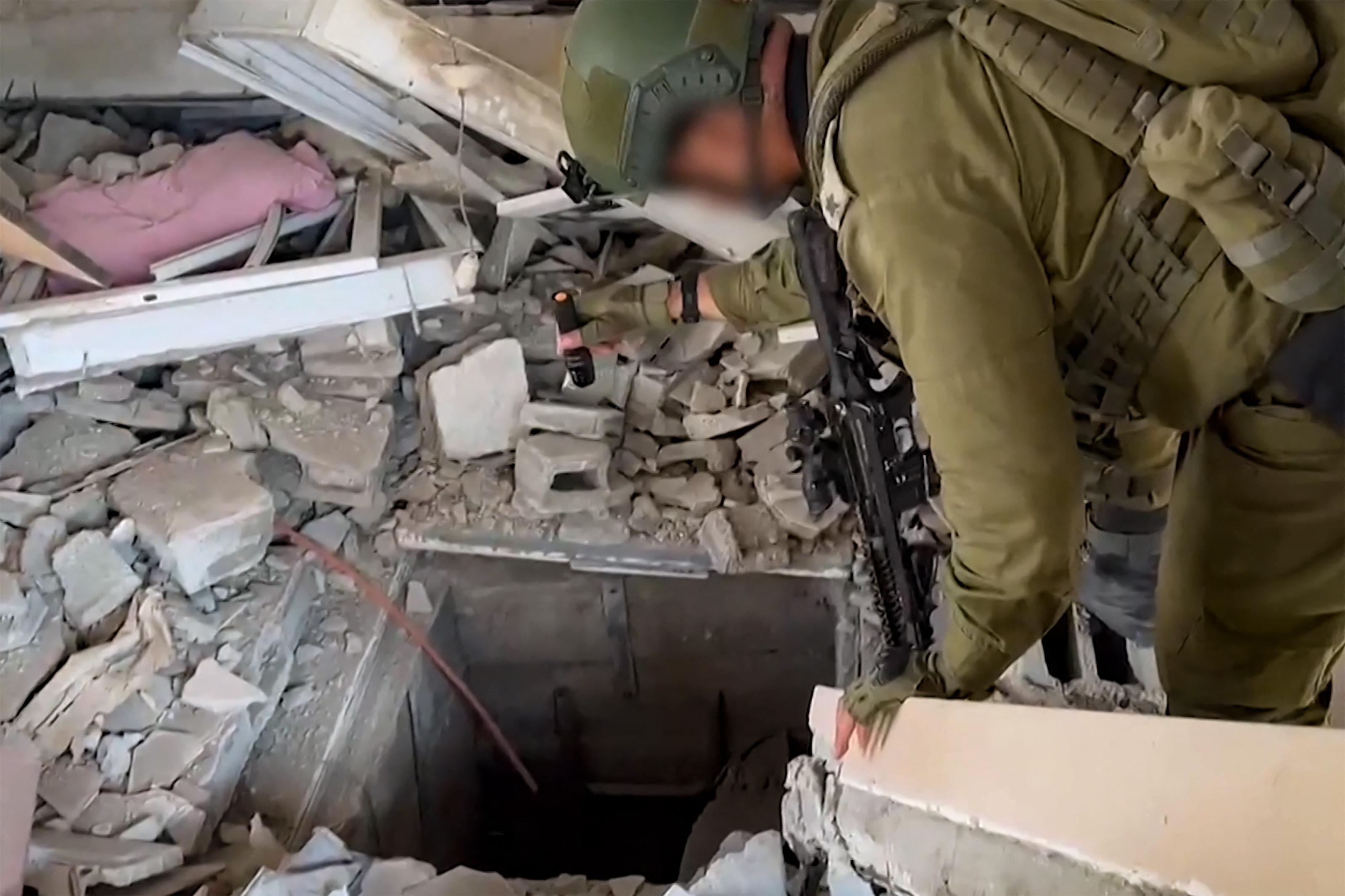 Un soldat se tient au-dessus de ce que l'armée israélienne présente comme l'entrée d'un tunnel du Hamas. [Israeli Army / AFP]