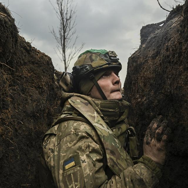 Le 8 mars 2023, un soldat ukrainien s'abrite dans une tranchée près de la ville de Bakhmout lors d'un bombardement. Plus d'un an après le lancement de l'"opération militaire" russe en Ukraine, le conflit s'enlise. [AFP - Aris Messinis]