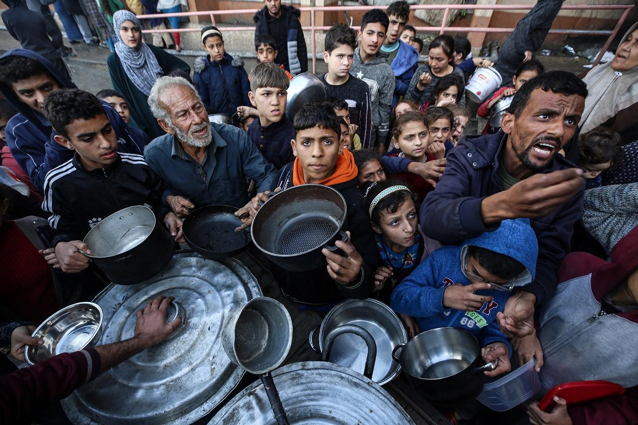 Des Palestiniens attendent de recevoir de la nourriture à un point de collecte, au centre de la bande de Gaza, le 24 décembre 2023. [AFP - Majdi Fathi / NurPhoto]