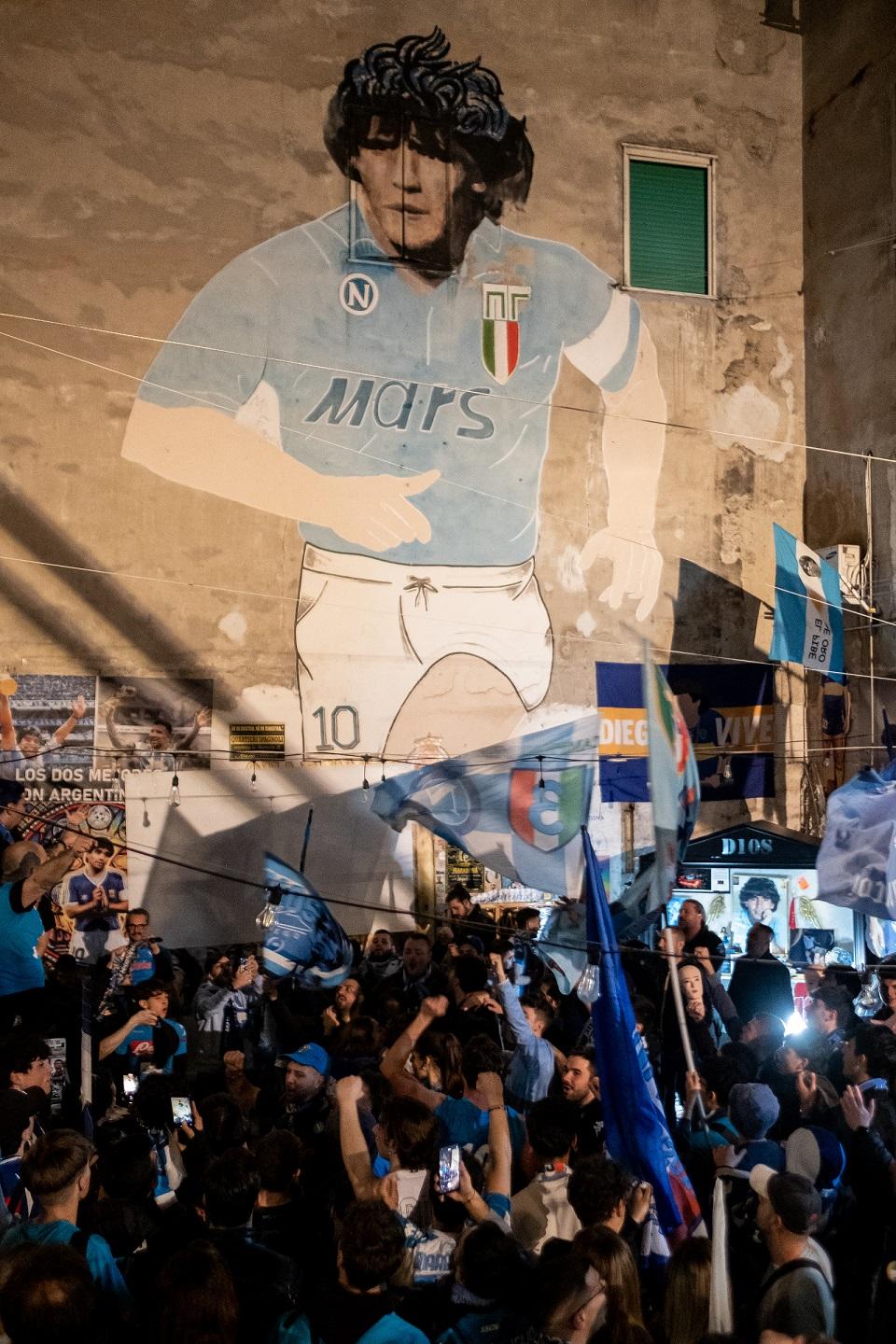 Des supporters de Naples célèbrent la victoire de leur équipe sous un portrait de Diego Maradona [AFP - SILVIA BAZZICALUPO]