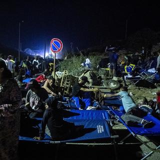 Des hommes et un enfant se reposent sur les lits du camp alors qu'ils attendent sur l'île italienne de Lampedusa, le 14 septembre 2023. [AFP - Alessandro Serrano]