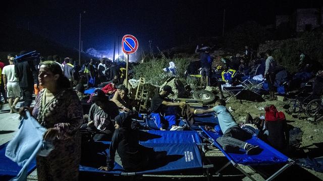 Des hommes et un enfant se reposent sur les lits du camp alors qu'ils attendent sur l'île italienne de Lampedusa, le 14 septembre 2023. [AFP - Alessandro Serrano]