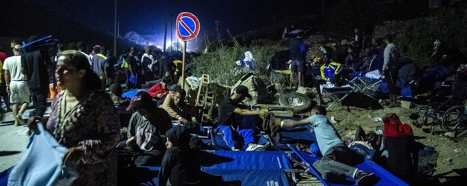 Des hommes et un enfant se reposent sur les lits du camp alors qu'ils attendent sur l'île italienne de Lampedusa, le 14 septembre 2023. [AFP - Alessandro Serrano]