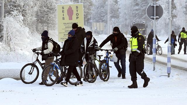 Des gardes-frontières finlandais et des migrants à vélo sont photographiés au poste-frontière international de Salla, en Laponie finlandaise, le 21 novembre 2023. [Jussi Nukari / Lehtikuva - AFP]