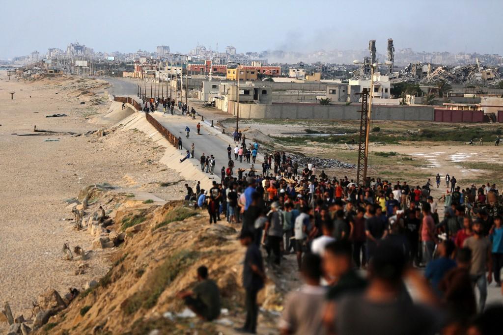 Des Palestiniens se rassemblent, le 19 mai 2024, dans l'espoir d'obtenir de l'aide livrée à Gaza par une jetée temporaire. [AFP - MAJDI FATHI]