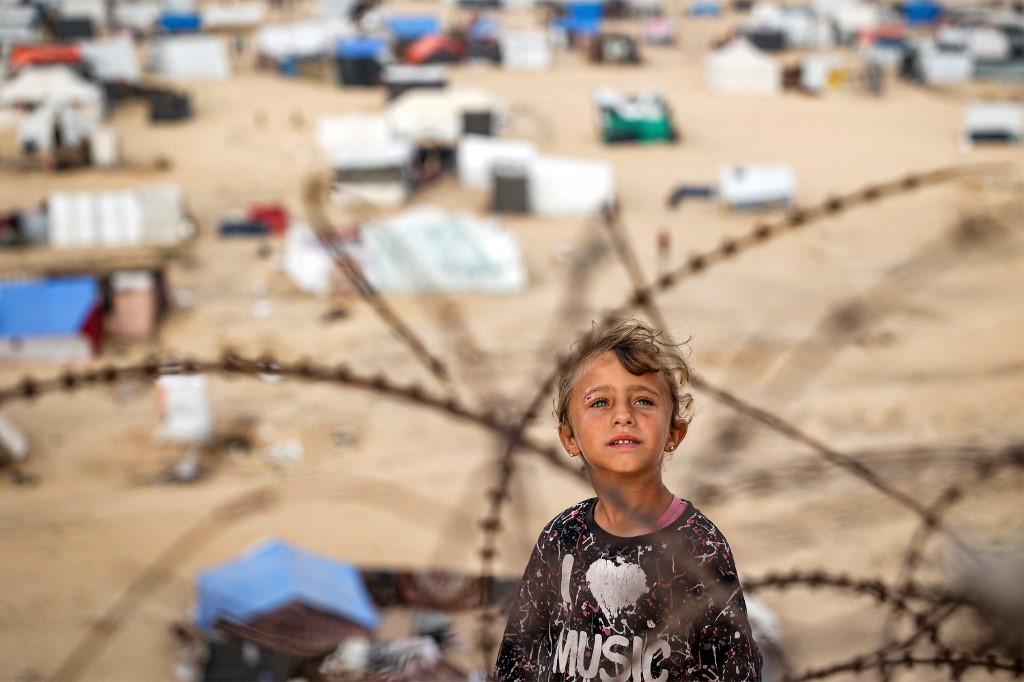 Une fille se tient derrière des barbelés à Rafah, dans le sud de la bande de Gaza. [AFP]