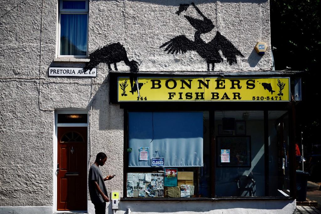 Une œuvre de l'artiste de rue Banksy, la cinquième à être publiée cette semaine, représentant deux pélicans attrapant du poisson, peinte sur le toit d'un magasin de fish and chips à Walthamstow, au nord-est de Londres. [AFP - BENJAMIN CREMEL]