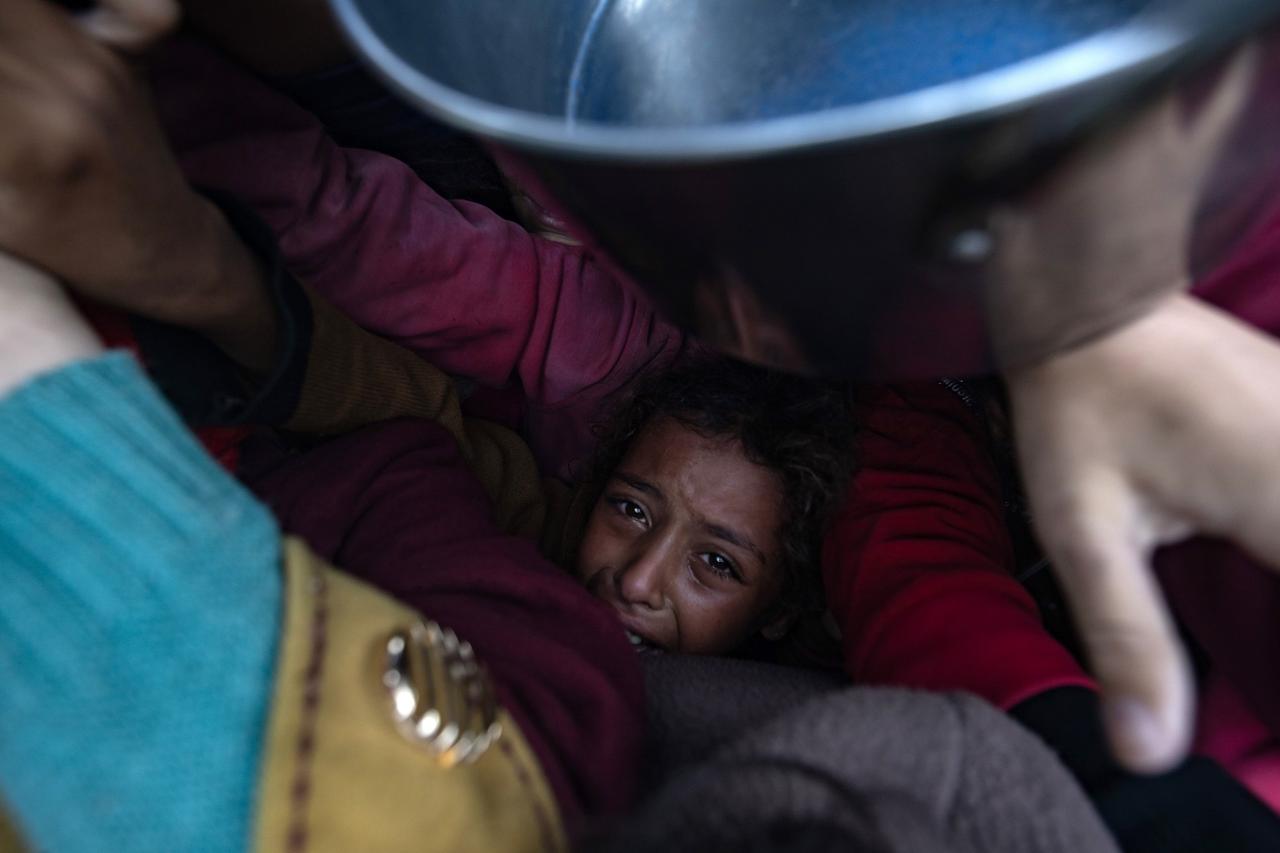 Un enfant en larmes se retrouve piégé dans une foule qui se bouscule lors d'une distribution de nourriture, à Khan Younès (sud de la bande de Gaza), le 29 novembre 2024. [KEYSTONE - HAITHAM IMAD]