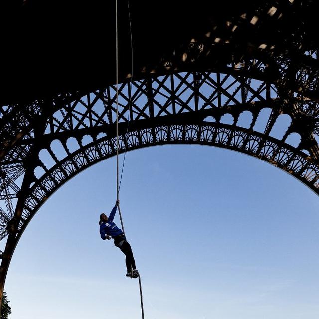 L'athlète française Anouk Garnier se hisse sur une corde jusqu'au deuxième étage de la tour Eiffel, à Paris, le 10 avril 2024. [AFP - STEPHANE DE SAKUTIN]