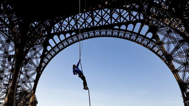 L'athlète française Anouk Garnier se hisse sur une corde jusqu'au deuxième étage de la tour Eiffel, à Paris, le 10 avril 2024. [AFP - STEPHANE DE SAKUTIN]