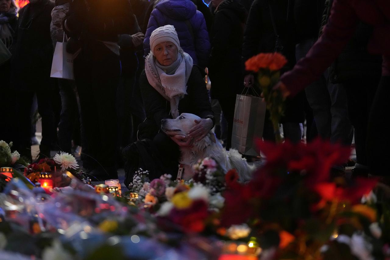 Des citoyens rendent hommage aux morts devant l'église Saint-Jean, près d'un marché de Noël où une voiture a foncé dans la foule vendredi soir, à Magdebourg, le samedi 21 décembre. [KEYSTONE - EBRAHIM NOOROZI]