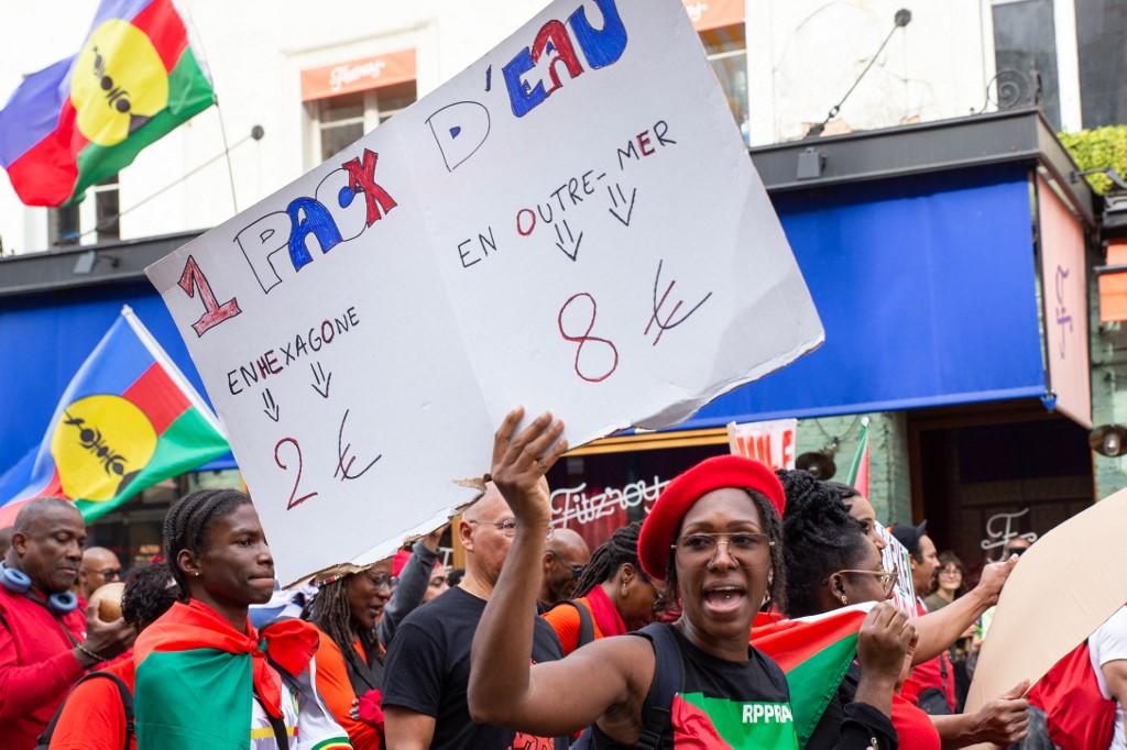 A Paris, une femme tient une pancarte en soutien aux manifestations contre la vie chère qui se deroulent en Martinique depuis la mi-septembre, le 21 septembre. [Hans Lucas via AFP - VALERIE DUBOIS]