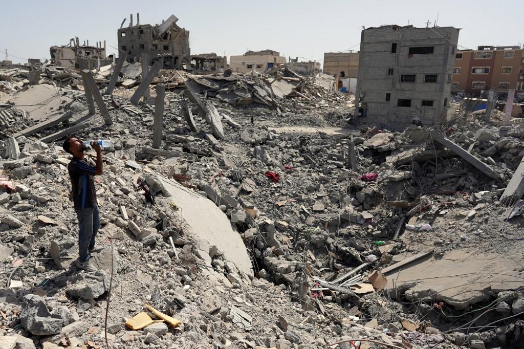 Un homme se tient au milieu des débris d'immeubles après une frappe israélienne la veille, à Khan Younès, dans le sud de la bande de Gaza, le 4 juillet. [AFP - BASHAR TALEB]