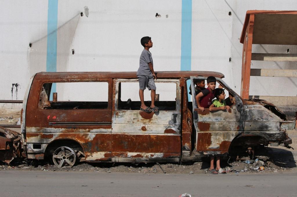Des enfants jouent dans une camionnette carbonisée à Rafah, dans le sud de la bande de Gaza, le 12 mai 2024. [AFP - -]
