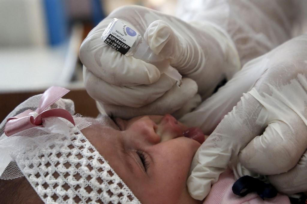 Un employé de l'UNRWA administre des vaccins contre la polio et les rotavirus à un bébé dans une clinique du camp de réfugiés de Bureij (bande de Gaza), en septembre 2020. [AFP - MOHAMMED ABED]