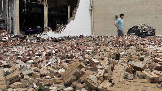 Un homme marche parmi les briques d'un bâtiment endommagé à la suite d'un violent orage, le 17 mai 2024, à Houston (Texas). [KEYSTONE - DAVID J. PHILLIP]