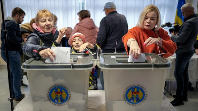 Deux femmes déposent leur bulletin dans l'urne à Chisinau, la capitale de la Moldavie, le 20 octobre 2024. [KEYSTONE - VADIM GHIRDA]