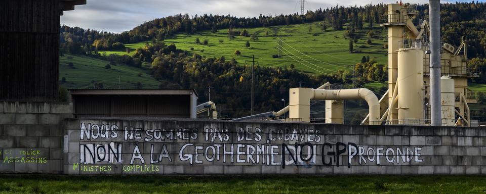 Une inscription "Non a la géothermie profonde" sur un mur à Glovelier, dans le canton du Jura. [Keystone - Jean-Christophe Bott]