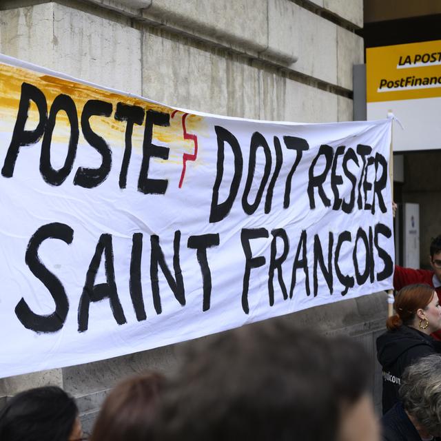 Les membres d'un comité pour le maintien de La Poste tiennent une banderole "La Poste doit rester a Saint-François", le jeudi 23 mars 2023 à Lausanne. [Keystone - Laurent Gillieron]