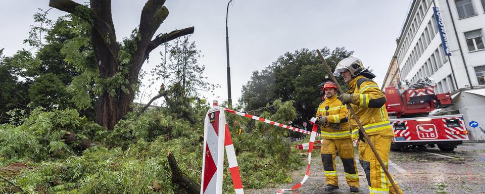 Des pompiers du SIS s'affairent après le très violent orage qui s'est abattu sur Genève. [Keystone - Martial Trezzini]