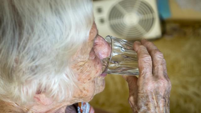 Une personne âgée s'hydrate pour se prévenir des fortes chaleurs. [Image d'illustration] [Keystone - Jean-Christophe Bott]