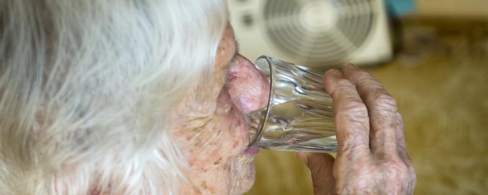 Une personne âgée s'hydrate pour se prévenir des fortes chaleurs. [Image d'illustration] [Keystone - Jean-Christophe Bott]