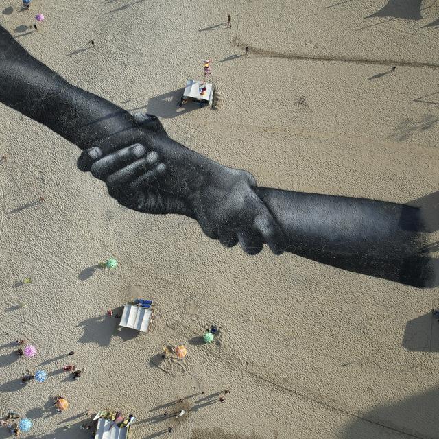 La Suisse doit "combler ses lacunes" en matière de protection des droits humains. (Sur la photo, une fresque de land art réalisée avec de la peinture biodégradable par l'artiste franco-suisse Saype, couvre la plage de Copacabana à Rio de Janeiro, au Brésil, le vendredi 15 juillet 2022). [Keystone - Silvia Izquierdo]