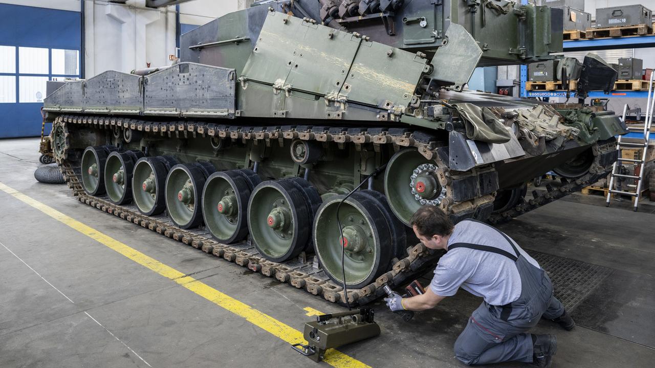 Un mécanicien entretient les chenilles d'un char de type Leopard 2 dans une halle de maintenance de RUAG, le 20 mars 2023, à Thoune. [Keystone - Peter Schneider]