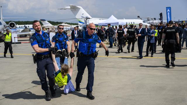 Des policiers évacuent les activistes du réseau Stay Grounded et Greenpeace qui manifestent sur le tarmac de l'aéroport de Genève le mardi 23 mai 2023. [KEYSTONE - LAURENT GILLIERON]