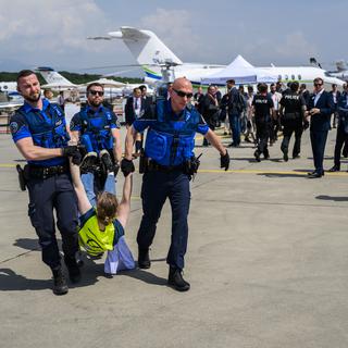 Des policiers évacuent les activistes du réseau Stay Grounded et Greenpeace qui manifestent sur le tarmac de l'aéroport de Genève le mardi 23 mai 2023. [KEYSTONE - LAURENT GILLIERON]