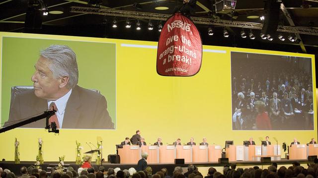 Deux militants sont entrés par le toit du Palais de Beaulieu pour déployer leur banderole. Sur l'écran, Peter Brabeck, président du conseil d'administration.