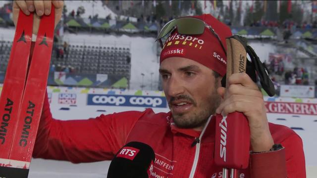 Planica (SLO), skiathlon messieurs: Jonas Baumann (SUI) au micro de la RTS dans l'aire d'arrivée