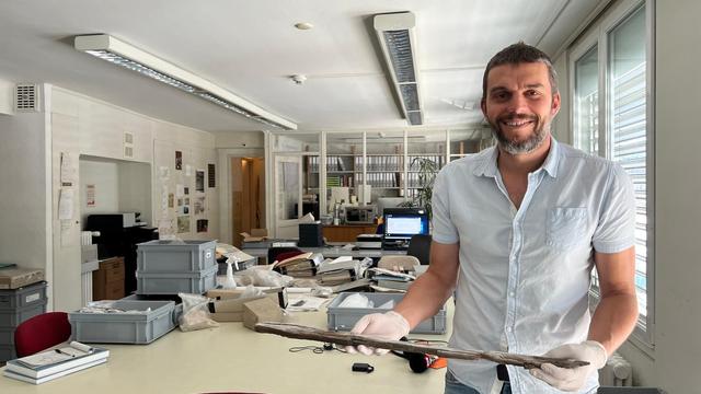 L’archéologue Romain Andenmatten tient dans ses mains un bois vieux de 2’500 ans, les plus vieux "skis" du Valais retro [RTS - Stéphane Délétroz]