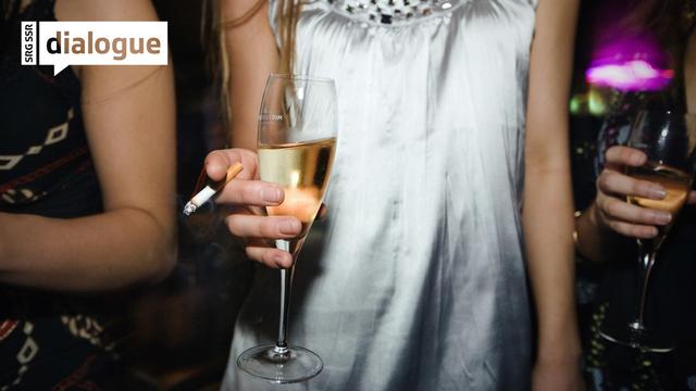 Une jeune femme photographiée dans un établissement nocturne tient dans sa main une cigarette et une coupe de vin mousseux. [KEYSTONE - MARTIN RUETSCHI]
