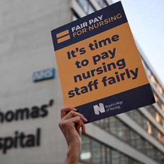 Une infirmière tient une pancarte pendant la grève à Londres. [Keystone - EPA/Andy Rain]